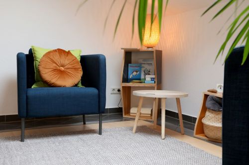 Zwei blaue Sessel stehen in einer Ecke mit einem kleinen Tisch